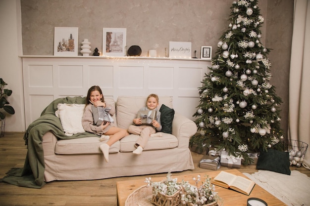 Bruder und Schwester sitzen mit Geschenken zu Hause auf der Couch. Neujahrskonzept