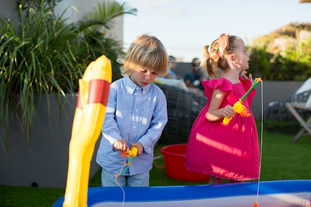 Bruder und Schwester spielen Angeln im Kinderbecken