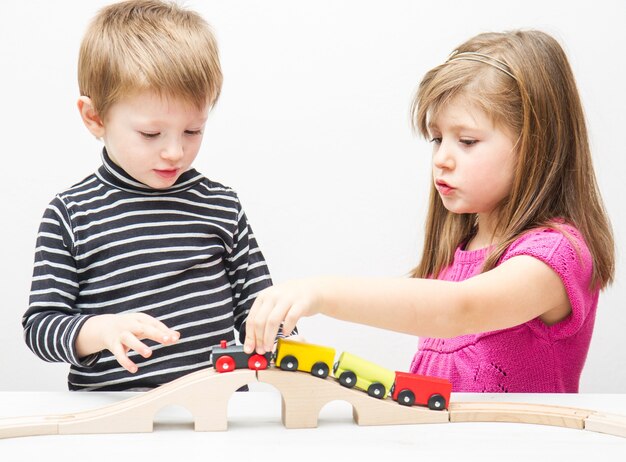 Bruder und Schwester spielen mit Holzeisenbahn