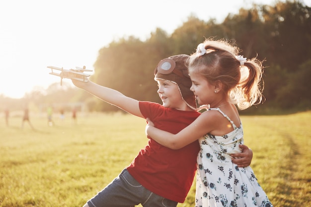 Bruder und Schwester spielen zusammen. Zwei Kinder, die mit einem hölzernen Flugzeug im Freien spielen