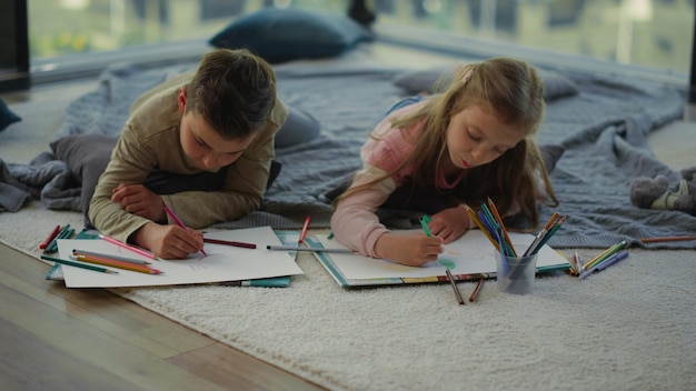 Bruder und Schwester zeichnen mit Buntstiften Kinder, die zu Hause Kunst machen