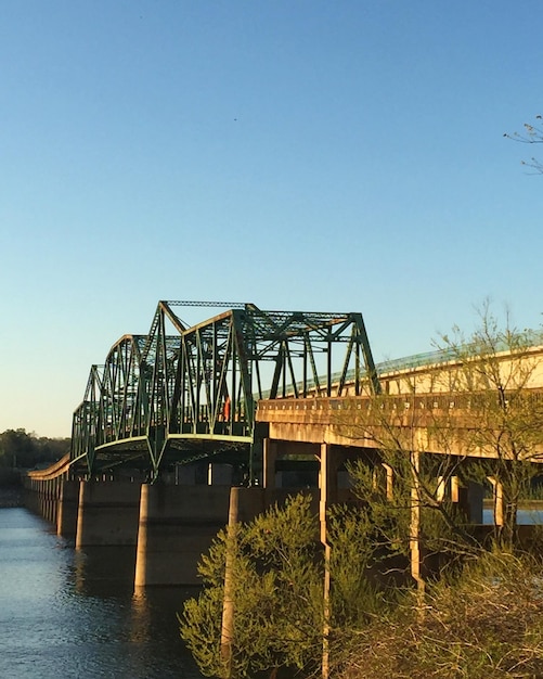 Foto brücke über den fluss gegen den klaren blauen himmel