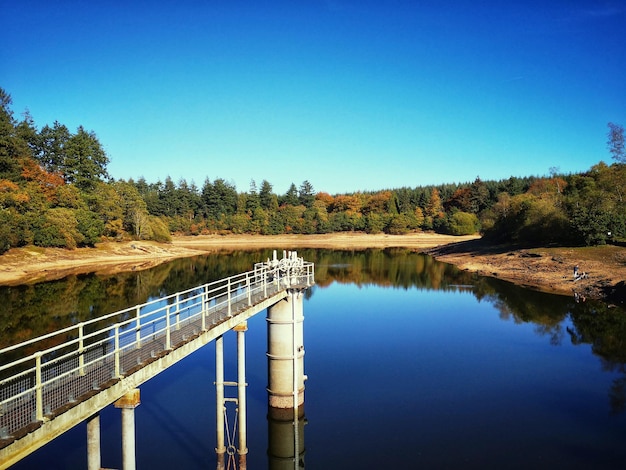 Foto brücke über den fluss gegen den klaren blauen himmel