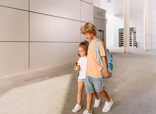 Foto brüder gehen mit rucksack und fußball zur schule.