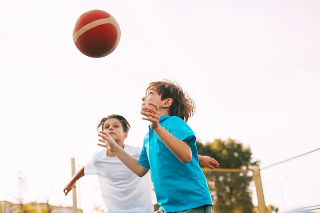 Brüder spielen Basketball gegen einen klaren Himmel