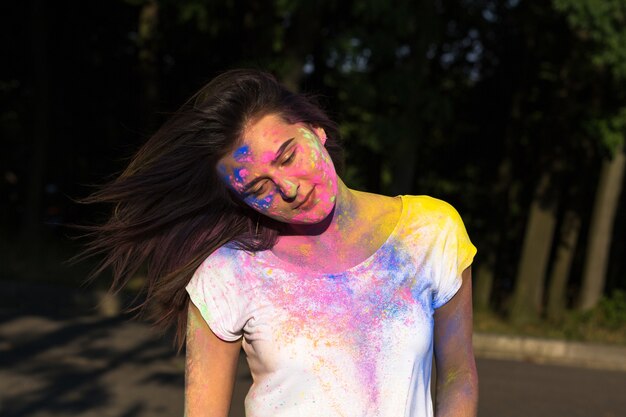 Brünette attraktive Frau mit Haaren in Bewegung, die Spaß mit Holi-Pulver hat