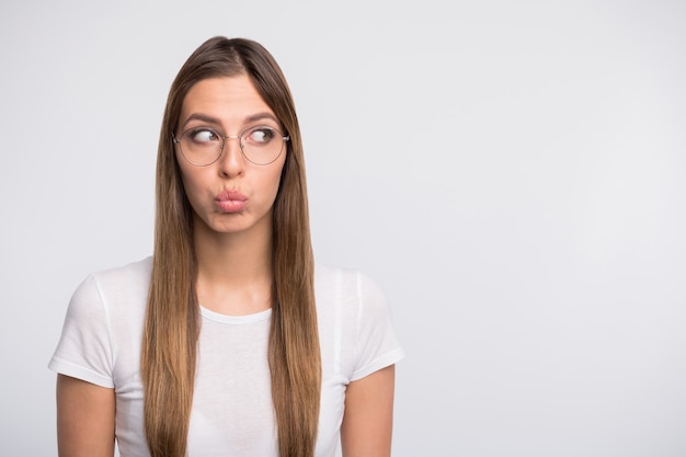 Brünette Dame mit Brille posiert gegen die weiße Wand