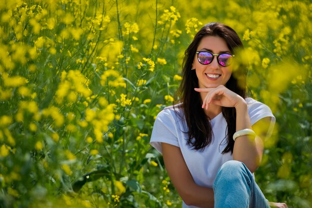 Brünette Frau in der Sonnenbrille in der Mitte des blühenden Feldes