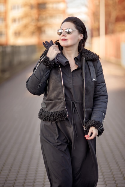 Brünette Frau in einer braunen Jacke und Sonnenbrille