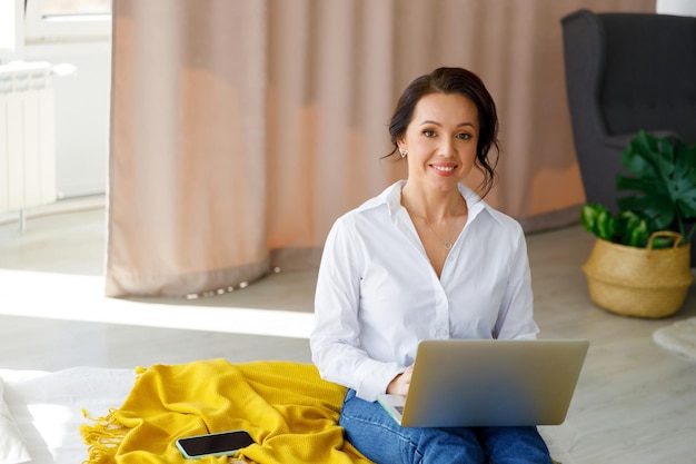 Brünette Frau in weißem Hemd und Jeans Freelancer arbeitet am Laptop zu Hause Weiblich im Geschäft