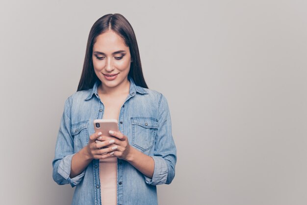 Brünette Frau mit Jeansjacke hält ihr Telefon