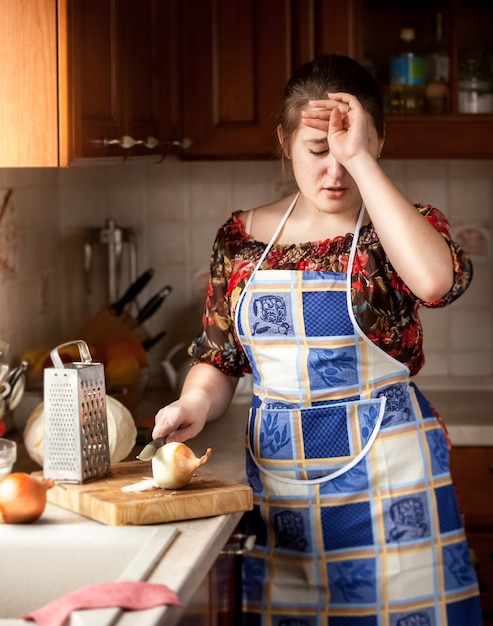 Brünette Hausfrau weint beim Zwiebelschneiden