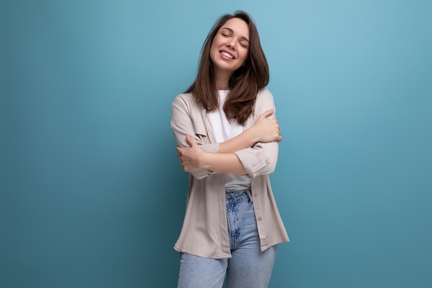 Brünette junge erwachsene Frau in Hemd und Jeans lächelt im Hintergrund mit Kopierraum