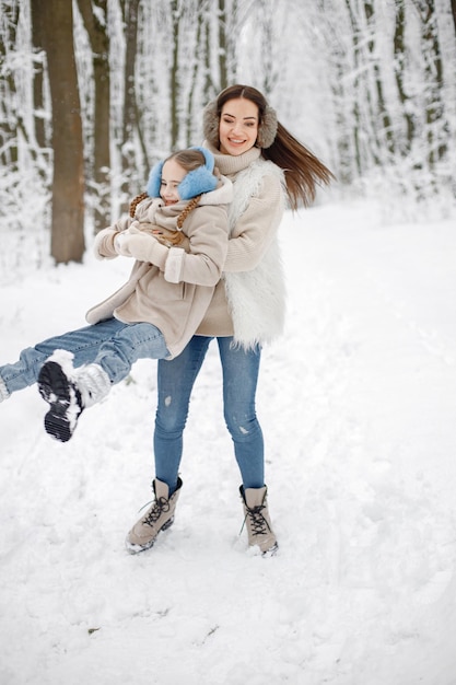 Brünette Mutter und ihre Tochter haben Spaß im Winterwald