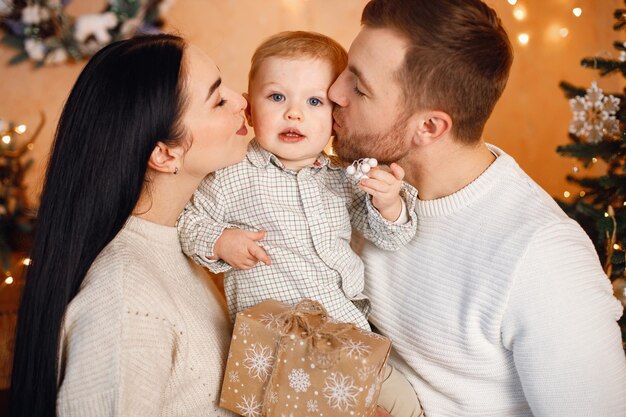 Brünetter Muttervater und kleiner Sohn stehen neben Weihnachtsbaum und umarmen sich