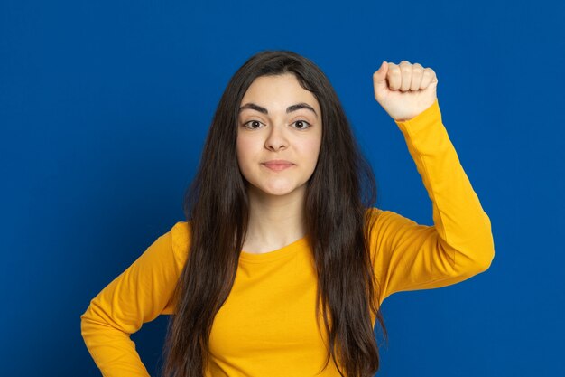 Brünettes junges Mädchen, das gelbes Sweatshirt trägt