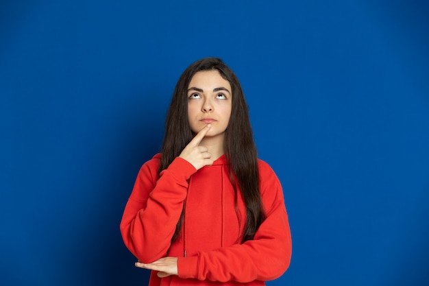 Brünettes junges Mädchen, das rotes Sweatshirt trägt