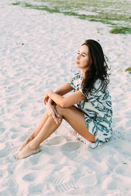 Brünettes Mädchen in einem eleganten Sommeroutfit und Strohhut in den Sonnenstrahlen auf einem Naturspaziergang