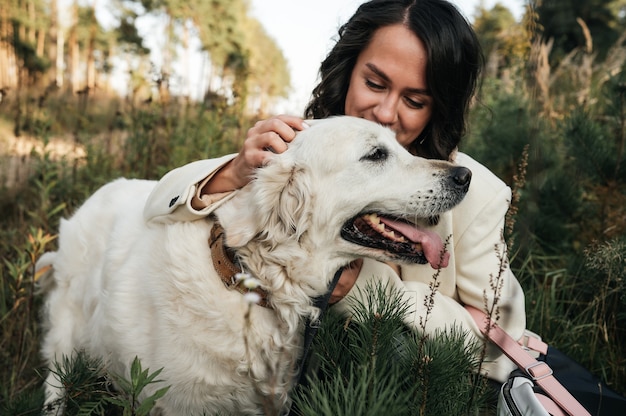 Brünettes Mädchen mit dem weißen goldenen Retrieverhund im Feld