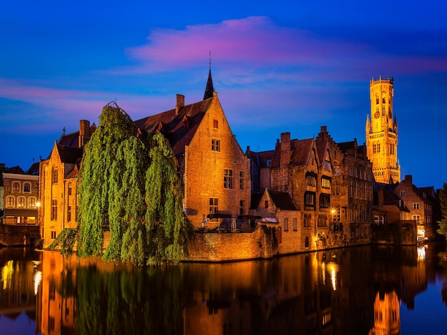 Bruges Rozenhoedkaai con campanario y casas antiguas a lo largo del canal con árbol en la noche Bruges Bélgica