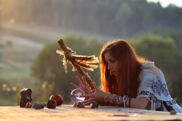 Bruja con bola de cristal al atardecer