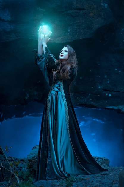 Foto la bruja con bola mágica en sus manos provoca espíritus en cueva.