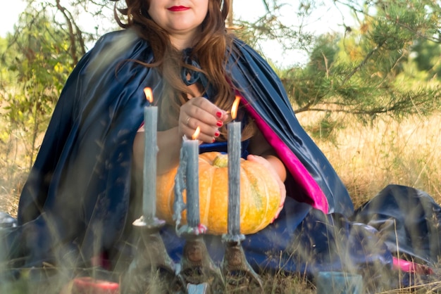 Una bruja en el bosque enciende velas en un viejo candelabro