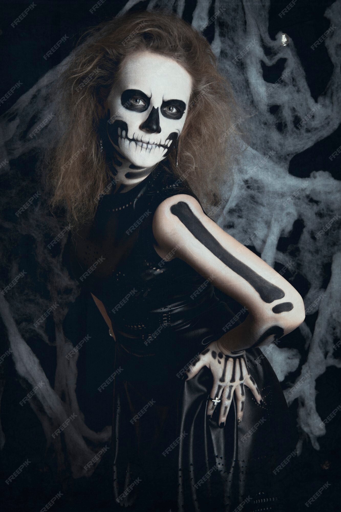 Bruja esqueleto chica posando con telarañas en negro | Foto Premium