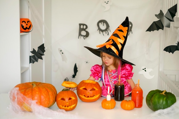 La bruja con un gran sombrero negro mira dentro de una calabaza aterradora tallada