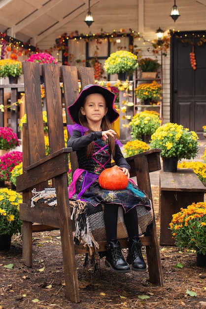 Bruja hermosa niña con calabaza en el parque al aire libre