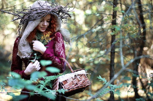 La bruja pelirroja realiza un ritual con una bola de cristal en el bosque.