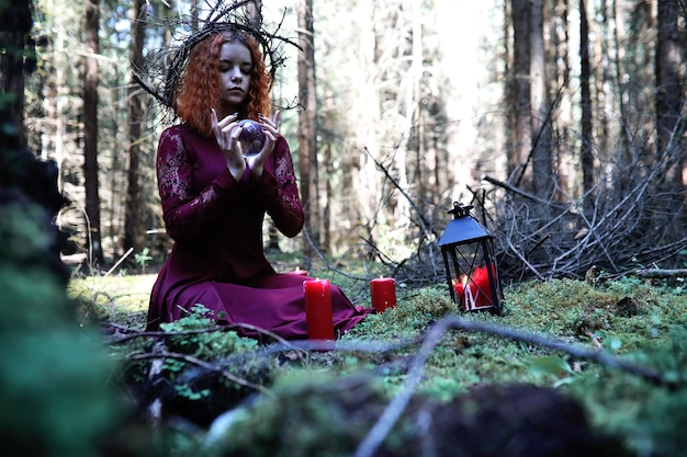 La bruja pelirroja realiza un ritual con una bola de cristal en el bosquexA