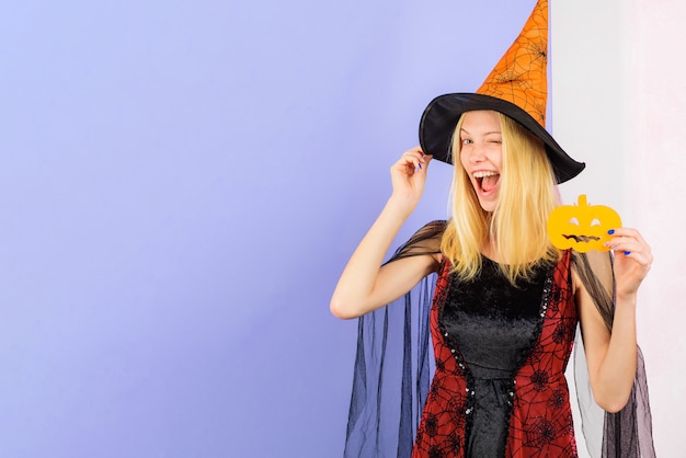 Bruja sonriente con calabaza tallada en papel. Guiño de niña con sombrero de brujas y disfraz de Halloween. Tallar calabaza. 31 de octubre.
