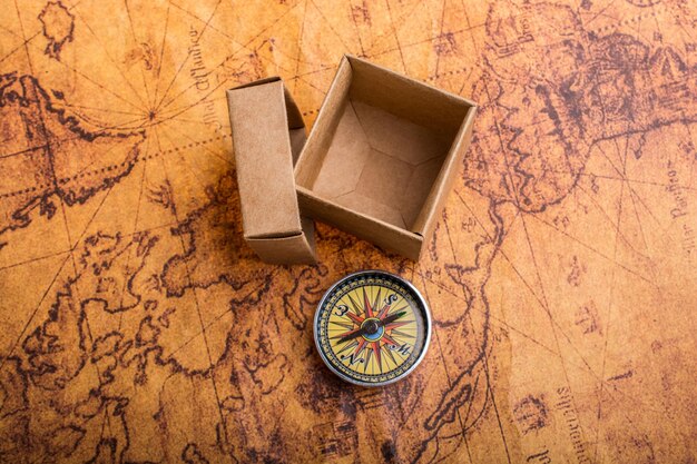 La brújula al lado de una caja en un mapa como concepto de viaje