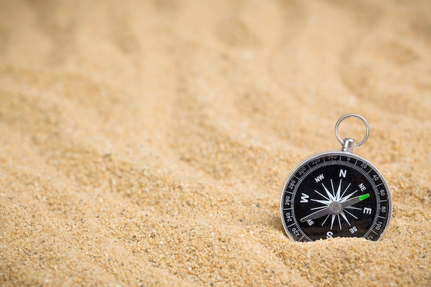 Brújula en la arena del mar en el fondo de la playa con espacio de copia para agregar mensajes de texto o usar componentes para el diseño Destino de viaje de verano y telón de fondo del concepto de navegación