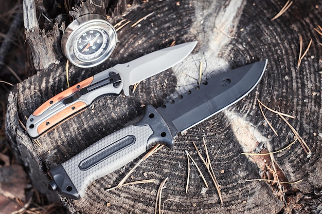 brújula y cuchillo en un tronco en el bosque concepto de viaje