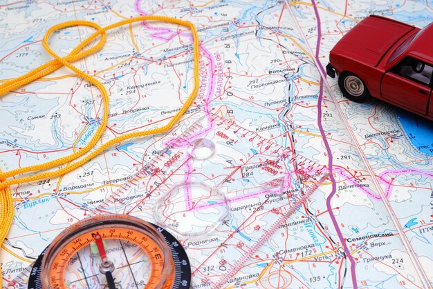 Foto brújula deportiva líquida y modelo del automóvil en un fragmento de un mapa