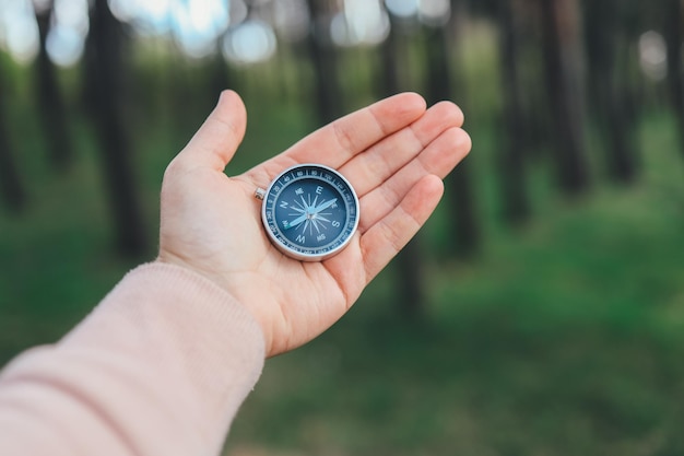 Brújula en la mano sobre el fondo de la naturaleza