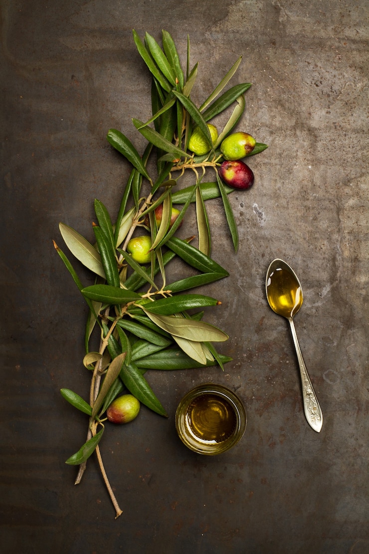 Brunch de aceitunas con hojas y aceite de oliva en un vaso sobre una mesa de metal oxidado