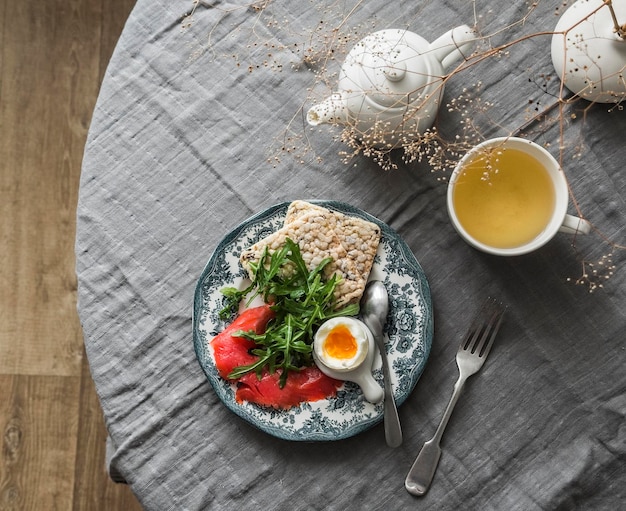 Brunch delicioso e saudável pequeno-almoço ovo cozido salmão ligeiramente salgado rúcula grão-de-bico pão crocante e chá verde na mesa vista superior