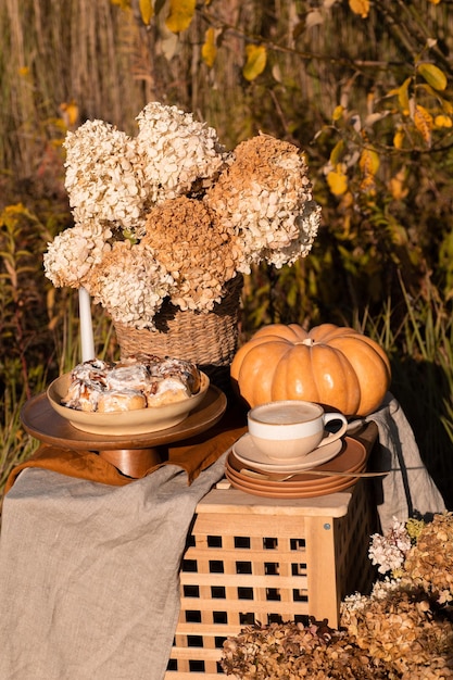 Un brunch festivo de otoño entre los árboles amarillos con calabazas, un café y un pastel, Acción de Gracias o una cena familiar en el patio trasero. Nadie