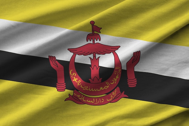Brunei Darussalam-Flagge mit großen Falten, die in der Nähe unter dem Studiolicht im Innenbereich winken Die offiziellen Symbole und Farben im Banner