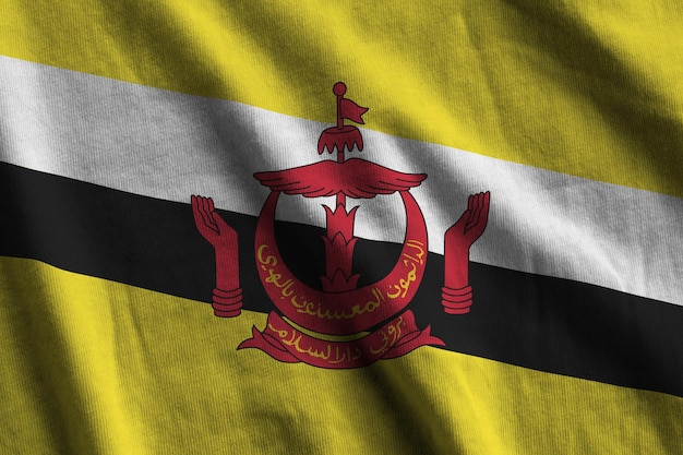 Brunei Darussalam-Flagge mit großen Falten, die in der Nähe unter dem Studiolicht im Innenbereich winken Die offiziellen Symbole und Farben im Banner