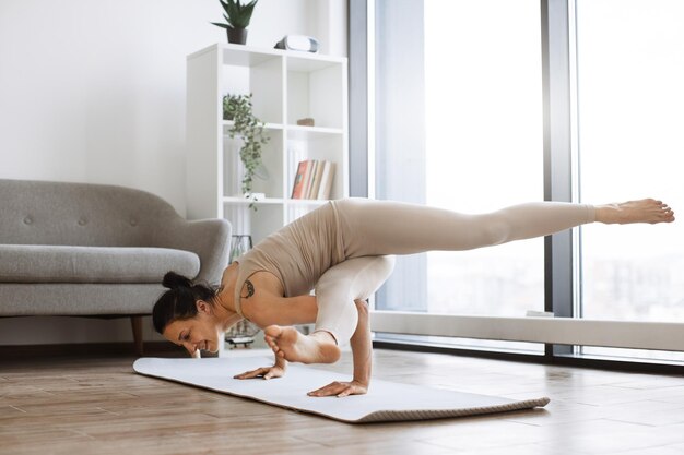 Bruneta practicando varias posiciones de resistencia corporal y equilibrio mientras entrena