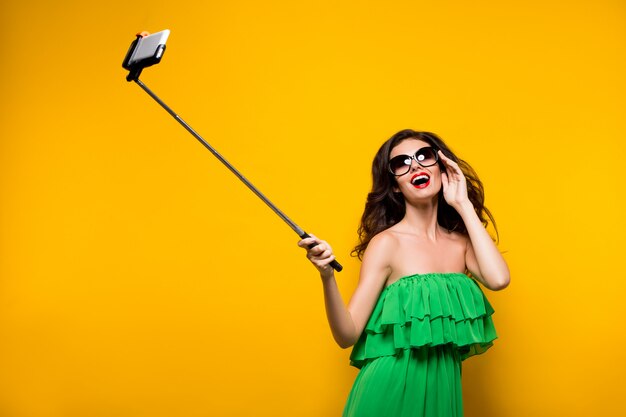 Brunette, der selfie in der Sonnenbrille und im grünen Kleid macht.