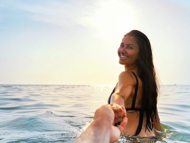 Brunette Frau, die Sommerbaden im Meer bei Sonnenuntergang genießt