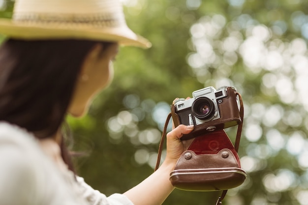 Brunette im Strohhut, der ein selfie mit Retro- Kamera nimmt