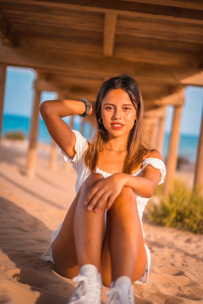 Brunette kaukasische Frau, die Urlaub auf dem Strand in einem weißen Kleid genießt