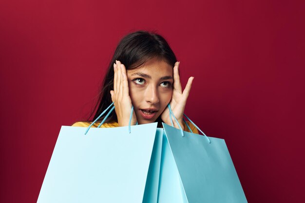 Brunette mit Paketen in den Händen, die roten Hintergrund kaufen