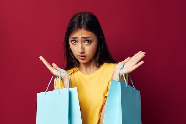 Brunette mit Paketen in den Händen, die roten Hintergrund kaufen